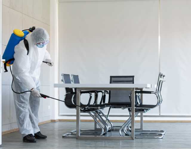Worker sanitizing public office area